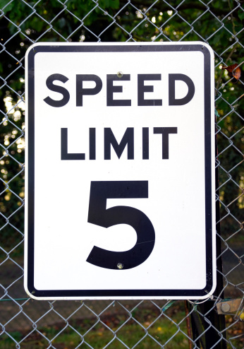 A speed limit sign of 5mph attached to a wire netting fence.