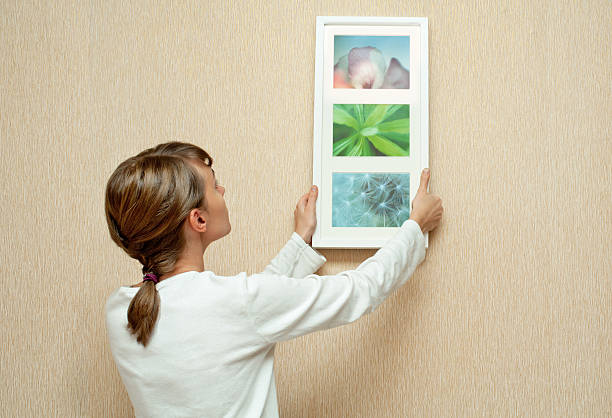 Decorating home Young woman hanging picture frame on the wall.  Pictures in the frame: I am the author, I own the copyright hanging photos stock pictures, royalty-free photos & images