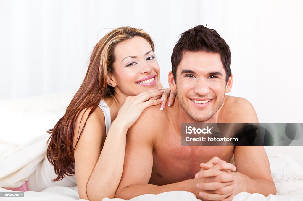 Feliz casal jovem deitado na cama de plumas - Foto de stock de 20-24 Anos royalty-free