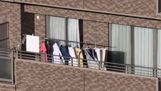 A residential balcony featuring suspended laundry items undergoing sun-drying throughout the day.