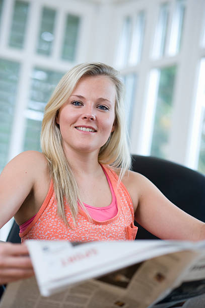 istock Smiling young woman reading newspaper 184853279