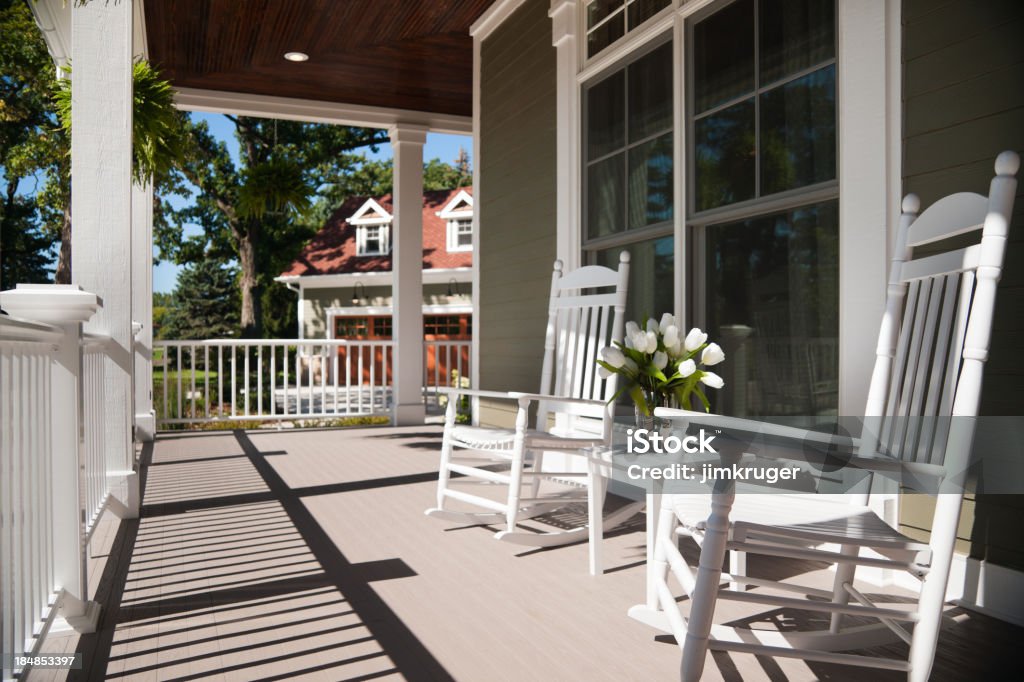 Wrap-around porch in summer. Summers day on the front wrap-around porch with two beautiful white enamel chairs and a vase of tulips. Focus on the foreground. Porch Stock Photo