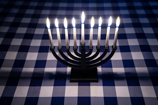 Low key Image of jewish holiday Hanukkah background with menorah (traditional candelabra) and burning candles and glitter overlay