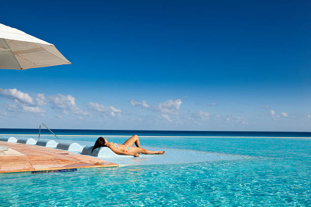 femme détente au complexe touristique de la piscine à débordement de l'hôtel de mexico - swimwear caribbean sea beach water photos et images de collection