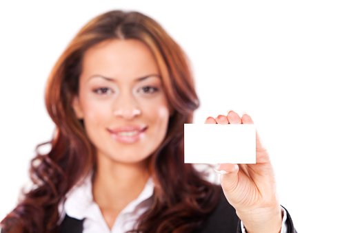 Portrait of young businesswoman holding blank business card, against white background. Selective focus.