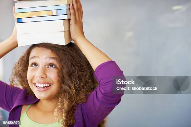 Photo libre de droit de Heureuse Jeune Fille Avec Des Livres Sur La Tête banque d'images et plus d'images libres de droit de Livre - Livre, Équilibre, Afro-américain