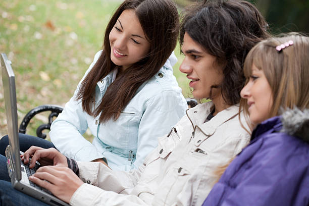 trois adolescentes avec ordinateur portable dans le parc - studygroup photos et images de collection