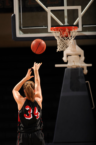 A female basketball player shoots a free throw. 