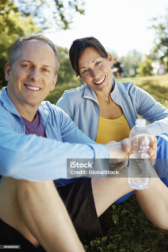 Couple sitting together after exercising Portrait of happy mature couple sitting together after exercising outdoors Exercising Stock Photo