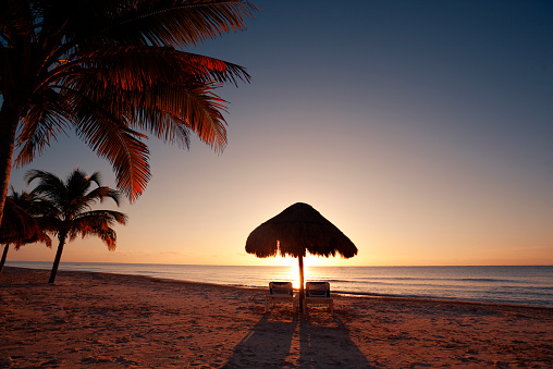 Subject: Tranquil beach palapa along the Caribbean Sea at sunrise.