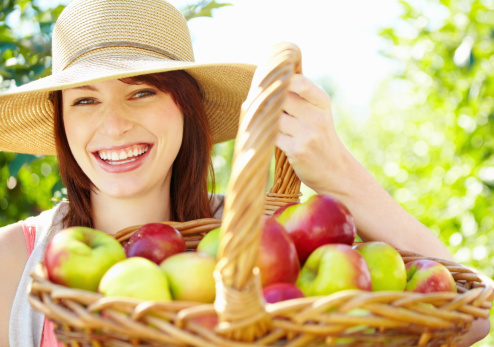 Closeup portrait of beautiful young woman holding basket full of apples