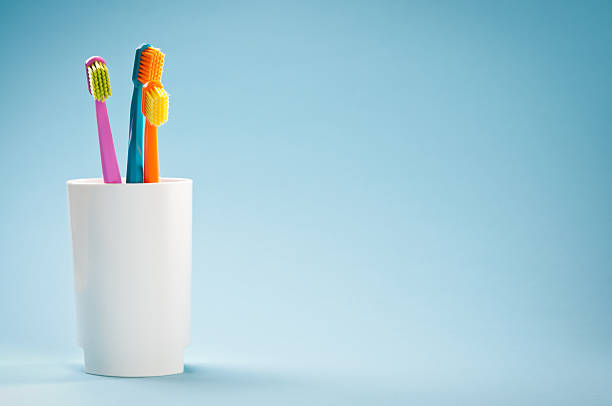 três colorido macio escovas de dente na caneca branca em fundo azul - toothbrush plastic multi colored hygiene - fotografias e filmes do acervo