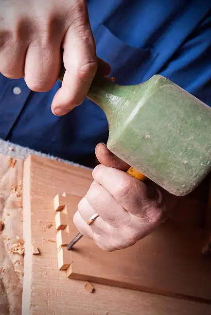 Detail image of woodworker using chisel to create dovetail joints