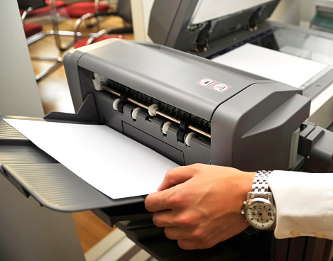 human hand takes a sheet out of the printer