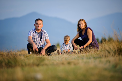 nice family posing in nature ; sitting on grass.