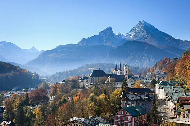 The city of Berchtesgaden in front of the Watzmann Mountains. European Alps, Germany. Trees colored by autumn.