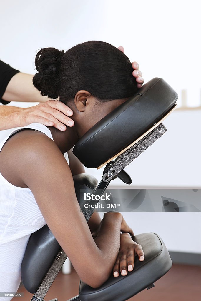 Woman in a Head Massage Chair Side view of a young woman getting a neck rub while seated in a massage chair. Vertical shot. Massaging Stock Photo