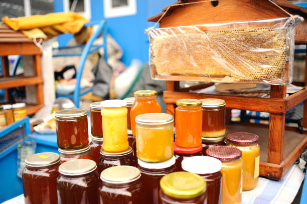 Deva, Romania - 2 September, 2019: selective focus color image depicting a large selection of fresh jars of honey for sale at a food market in Deva, a town in the Transylvania region of Romania. The honey comes in many different varieties and colors, and is made by small individual producers in the Transylvanian countryside. The jars are stacked on top of each other, creating an impressive display of honey.