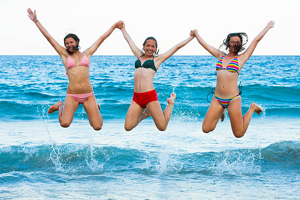 Subject: Playful young women vacationers having fun on the beach of tropical resort.