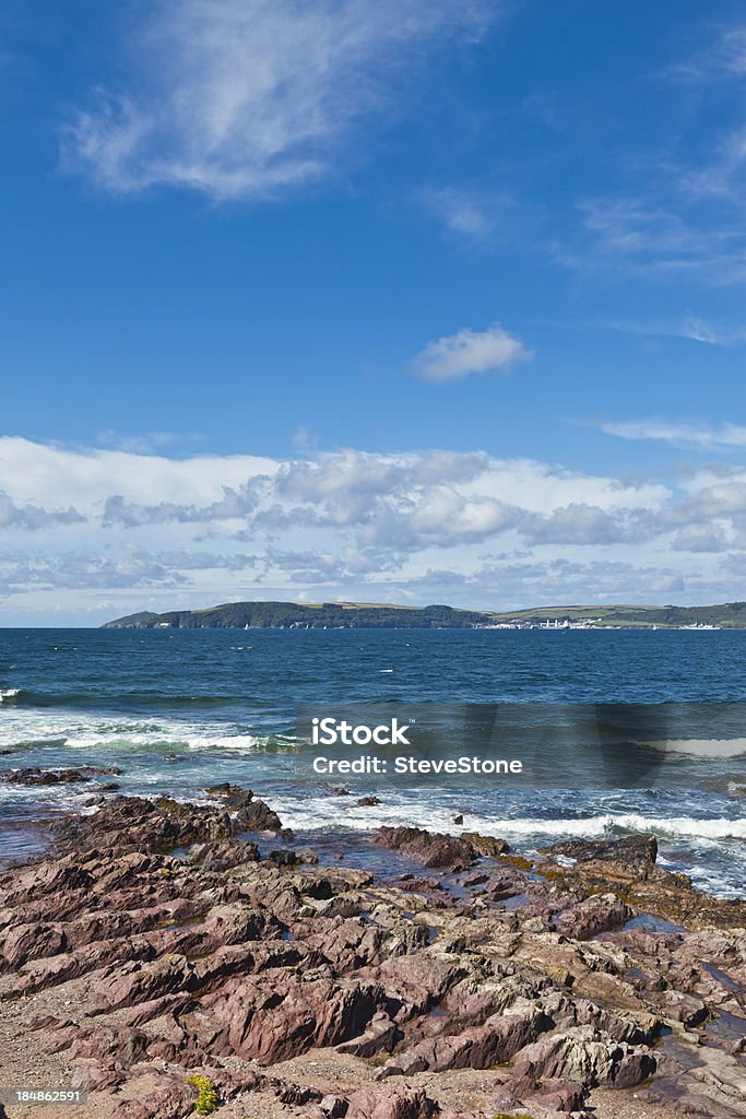 Blue sky and sea English coast Devon looking towards Cornwall A beautiful late summer landscape of the English Devon coast and beach. Looking over to Cornwall.  Sharp focus is on wave in mid frame. Adobe RGB 1998 profile Bay of Water Stock Photo