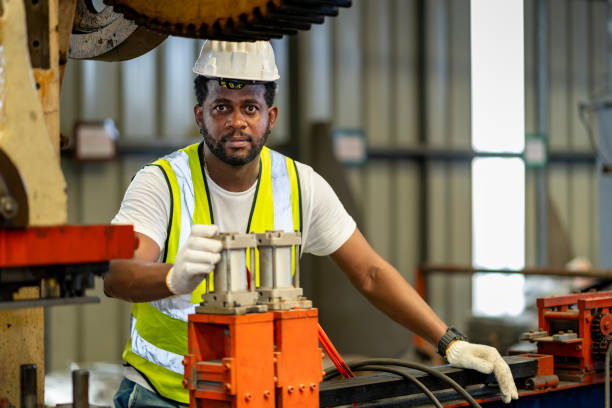 istock African American industrial worker is using hydraulic power press machine to make metal and steel part while working inside the metal sheet galvanized roof factory for safety industry 1848628765