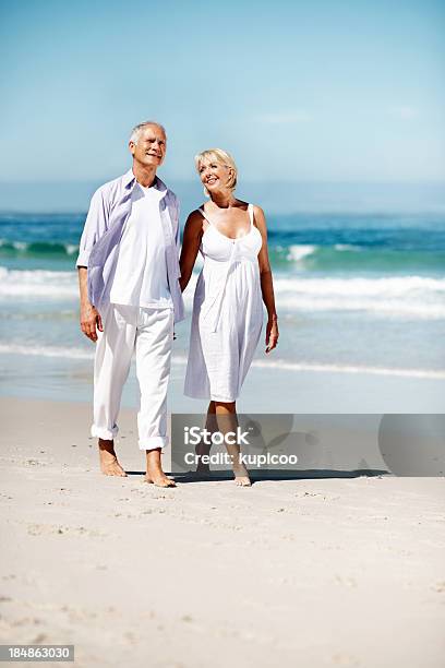 Photo libre de droit de Jeune Couple Marchant Le Long De La Plage banque d'images et plus d'images libres de droit de Couple senior - Couple senior, Plage, Retraite