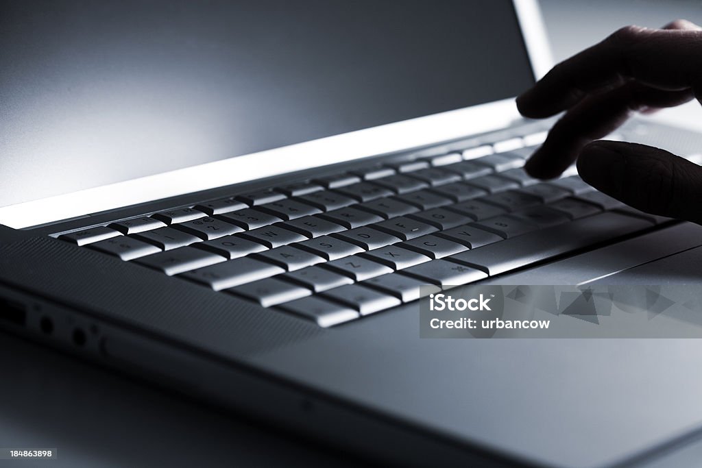 Typing on a Laptop Using a laptop, finger on keyboard Back Lit Stock Photo