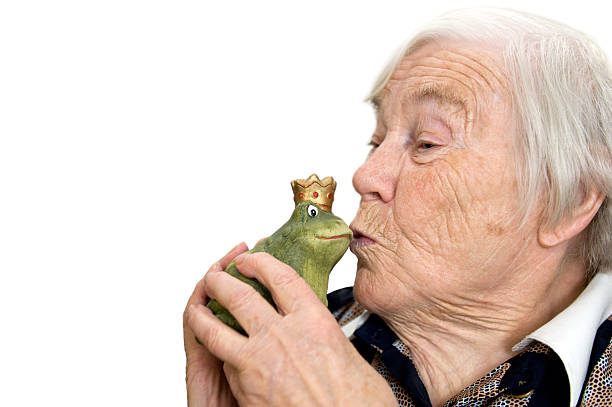 Female senior wants to kiss a frog king stock photo