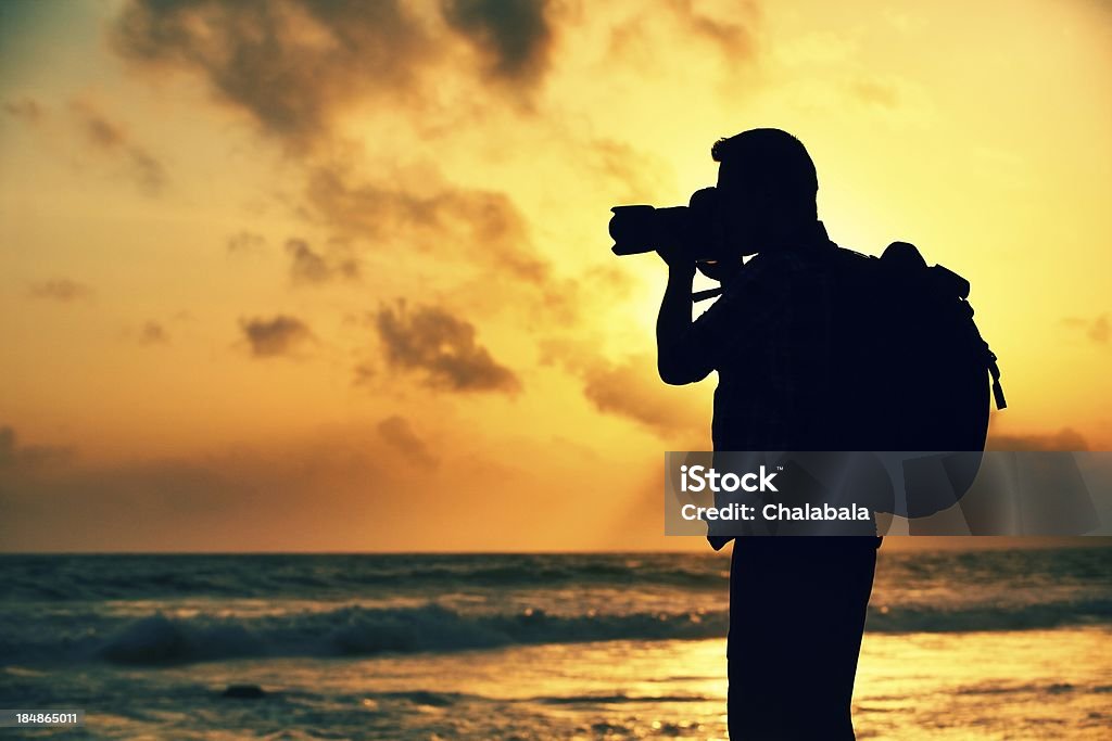 Close-up of photographer taking a picture at sunset Silhouette of young photographer on the beach  Adult Stock Photo