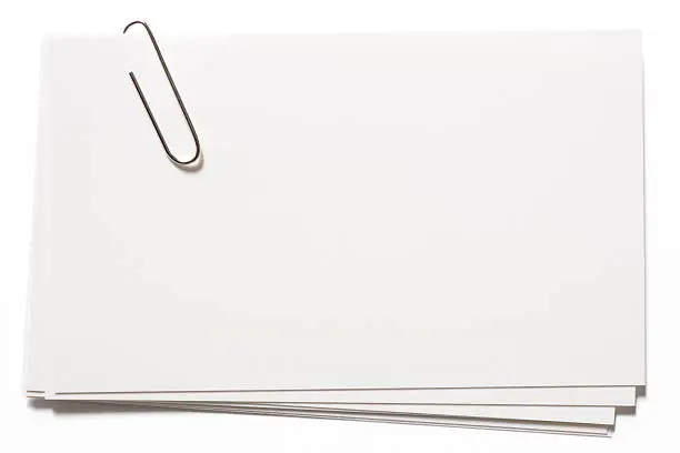 Photo of Stacked blank white cards with paper clip on white background