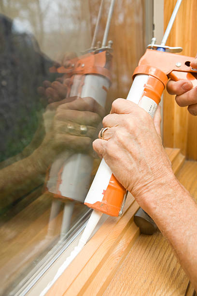 Hands Applying Weather Seal Caulk to Window Frame  winterizing stock pictures, royalty-free photos & images