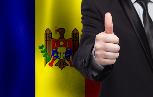 Moldovan concept. Businessman showing thumb up on the background of flag of Moldova