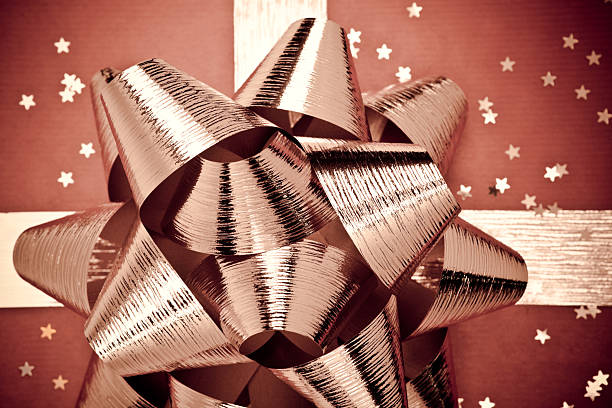 Tied bow golden ribbon on colorful holographic packaging paper closeup as a background