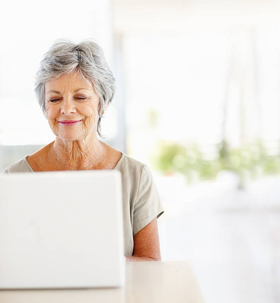 Mature woman using the internet Happy mature woman using a laptop at home gray hair photos stock pictures, royalty-free photos & images
