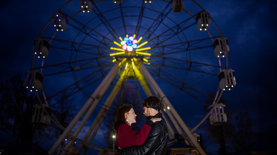 Caucasian couple in love in an amusement park hugging on a date.