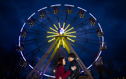 Caucasian couple in love in an amusement park hugging on a date.