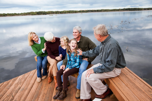 Family portrait, three generations sitting on wooden deck with view of Intracoastal Waterway, Florida.