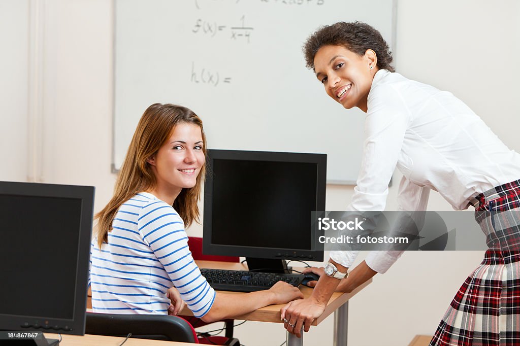 Professor e aluno trabalhando em computadores juntos - Foto de stock de Adolescente royalty-free