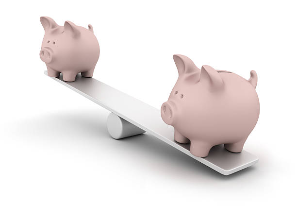 istock Two piggy banks on a balance scale 184868024