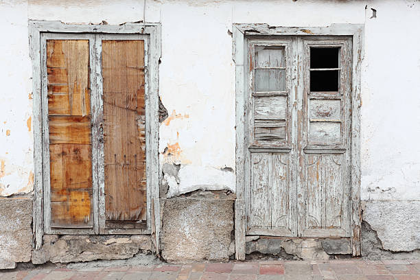 two worn out doors in white spanish housing facade