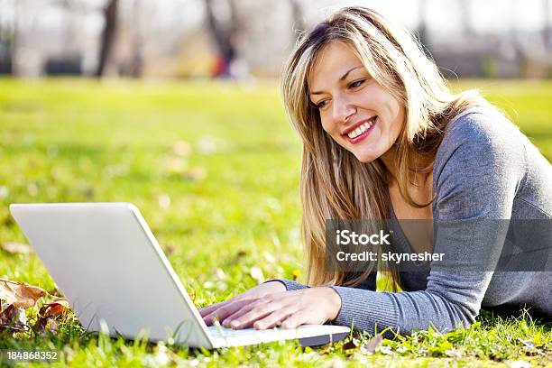 Foto de Jovem Mulher Usando Seu Laptop Em Um Parque e mais fotos de stock de Adulto - Adulto, Beleza, Beleza natural - Natureza