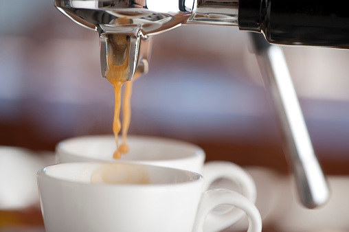 Close-up of two coffee cups in an espresso machine with blurred background
