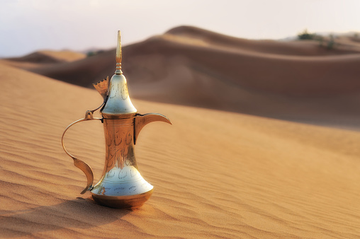 beautiful arabic coffee pot in desert landscape.  image was glow added, taken in dubai uae