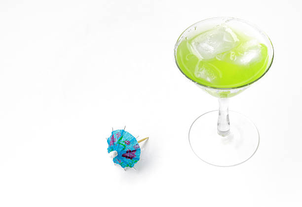 Exotic cocktail drinks. Summer vacation beach party alcohol. Fun green and purple cocktails with paper umbrellas and curly straws against graduated blue background.
