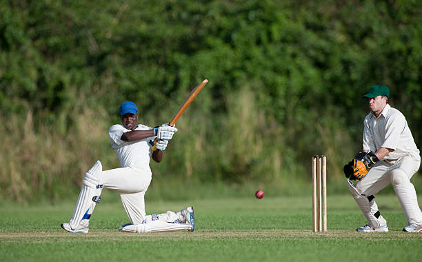 Cricket "Cricket action, batsman playing a sweep shot watched by the wicketkeeper." cricket player stock pictures, royalty-free photos & images