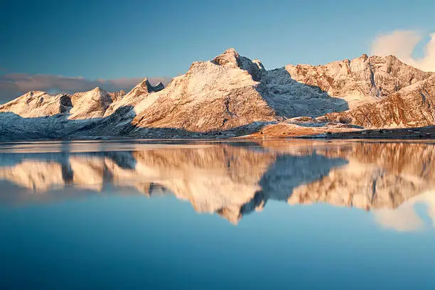 "Snow covered mountains reflected in a very calm fjord, Svolvaer, Lofoten Islands."