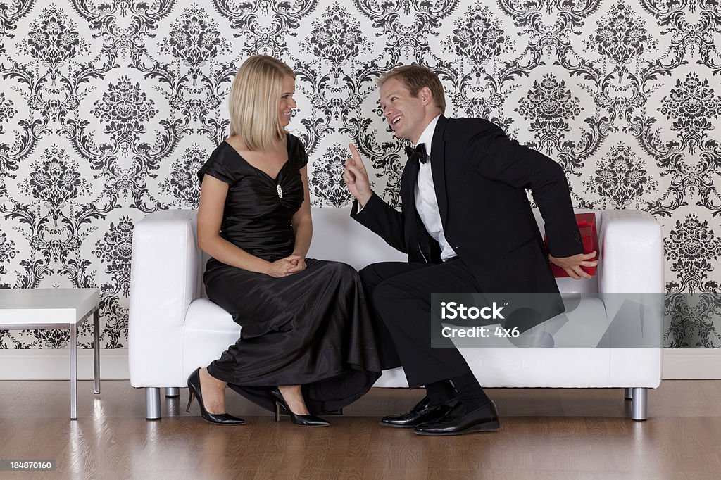 Coppia seduta su un divano - Foto stock royalty-free di Abbigliamento elegante