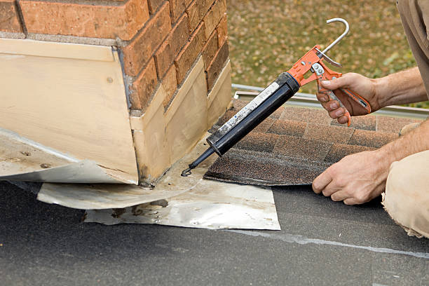 istock Roofer Applying Caulk to House Chimney Flashing 184870175