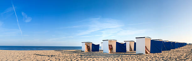 panorama view on rows of colorful empty beach huts at the North Sea coast at dawn in The Netherlands on a sunny day