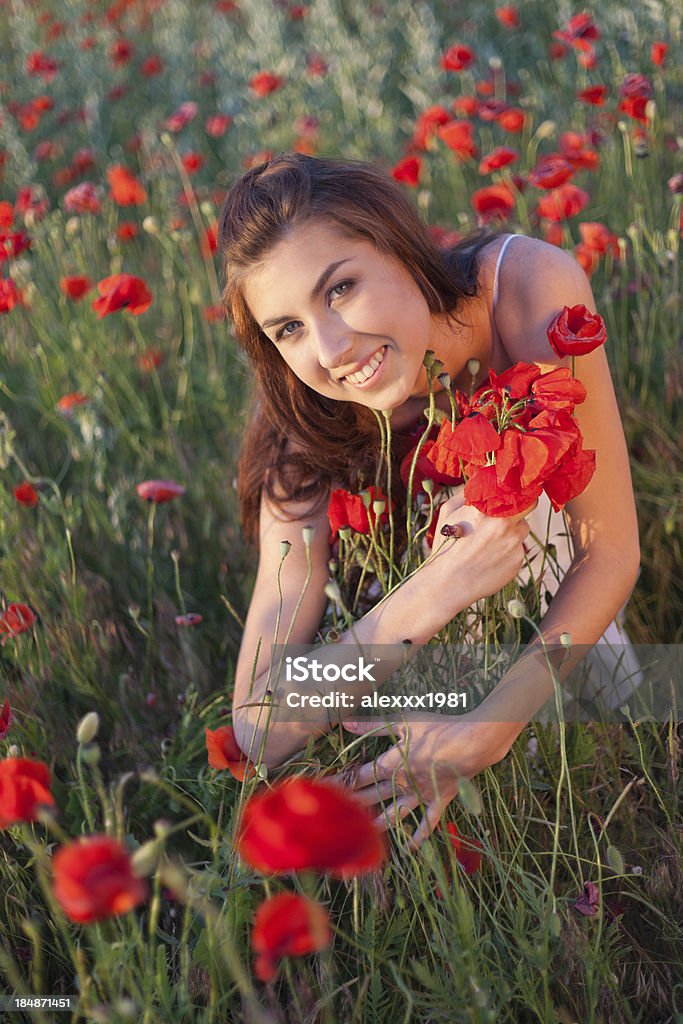 Jeune femme heureux embrassant armful de coquelicots à Floraison champ - Photo de Adulte libre de droits